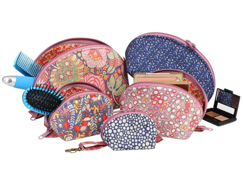 A collection of five floral patterned zippered bags in various sizes, with a comb and makeup palette.