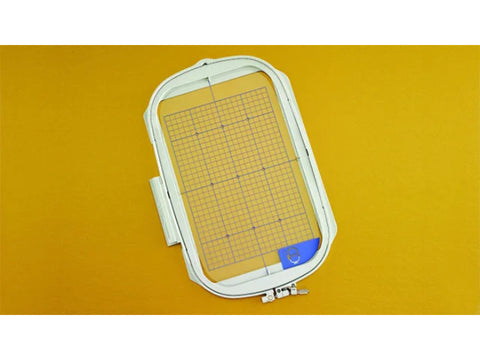 An 8 by 12 inch embroidery hoop with a grid on a yellow background.