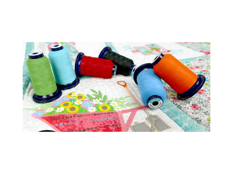 Six spools of matte finish embroidery thread in assorted bright colors are on a quilted fabric.