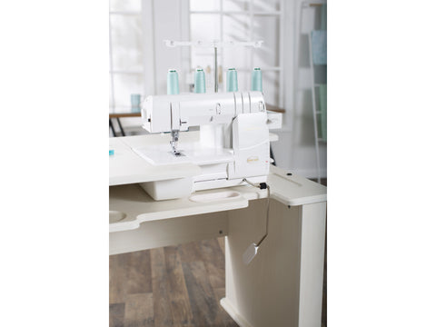 A white Baby Lock Euphoria cover stitch serger with light blue thread on a sewing table.