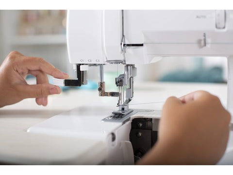 A person threads a white Baby Lock Euphoria cover stitch serger.