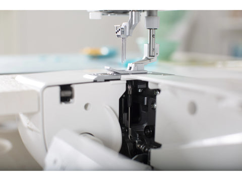 A close-up of a white Baby Lock Euphoria cover stitch serger with its front panel open.