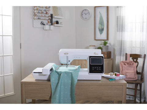 A white Baby Lock Flare embroidery machine with a light blue fabric on a wooden table.