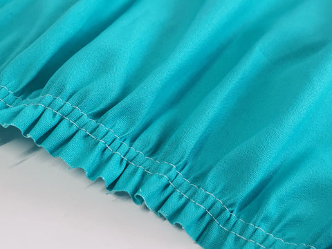 Close-up of a turquoise fabric with white stitching creating a ruffled edge.