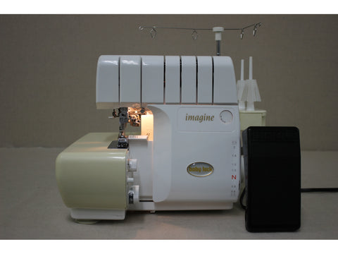 A pre-owned Baby Lock Imagine 2 serger in white and beige with a black foot pedal.