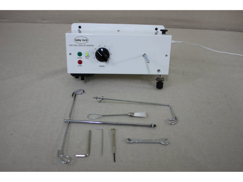 A white Baby Lock Coronet longarm quilting machine with various tools and accessories.