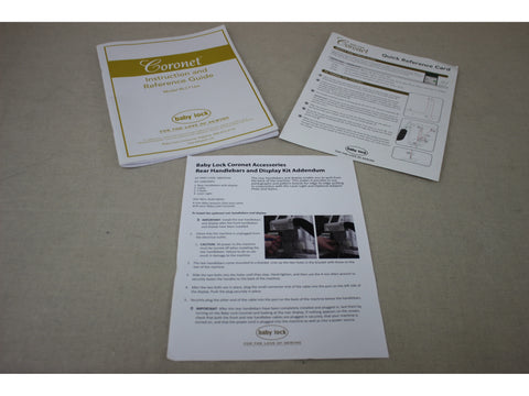 Three Baby Lock Coronet instruction manuals are displayed on a light gray surface.