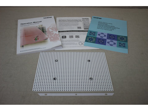 Brother Stellaire Innovis XJ1 manuals and a white perforated design sheet are displayed.
