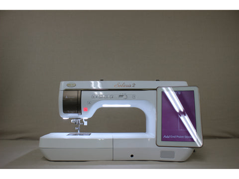 A white Baby Lock Solaris 2 sewing and embroidery machine with a lit screen.