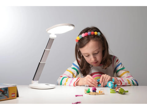 A white Foldi Go Rechargeable Table Lamp illuminates a child playing with building blocks.