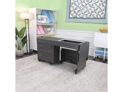 A dark gray sewing cabinet with an electric lift and storage drawers on wheels.