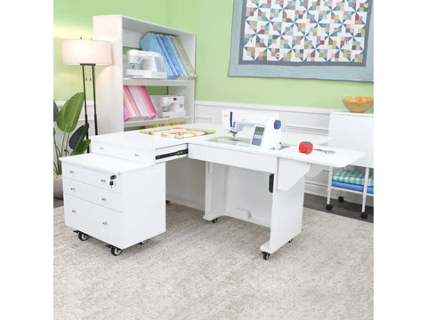 White sewing cabinet with an electric lift and rolling storage caddy in a craft room.