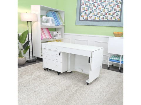 White sewing cabinet with an electric lift, two collapsible leaves, and a rolling storage caddy.