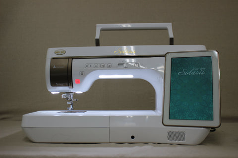 A white Baby Lock Solaris sewing and embroidery machine with a lit screen.
