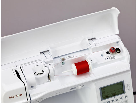 A white Baby Lock Lyric sewing machine with a red spool of thread on top.