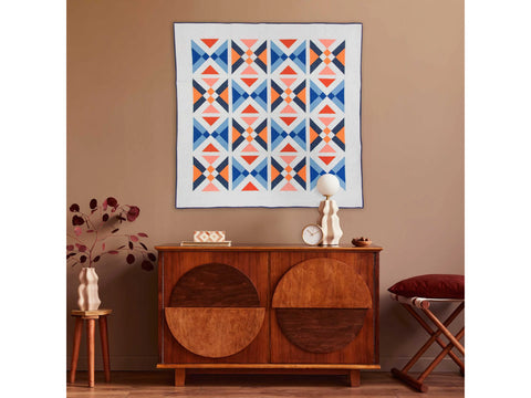 A quilt with a repeating pattern of blue, orange, and pink triangles.