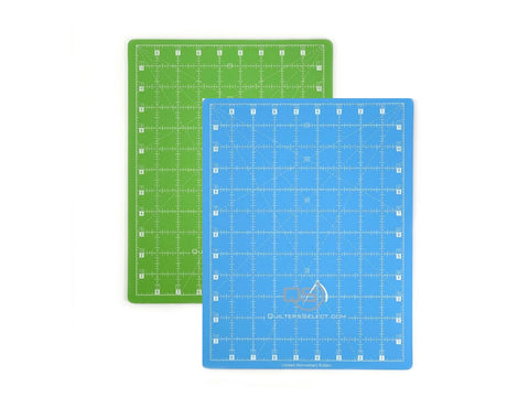 Two dual-sided cutting mats, one green and one blue, are shown on a white background.