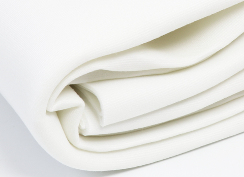 A roll of white Soft & Stable fabric is folded, showing its thickness and texture.