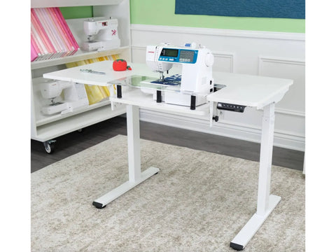 White electric height-adjustable sewing and cutting table with a sewing machine.