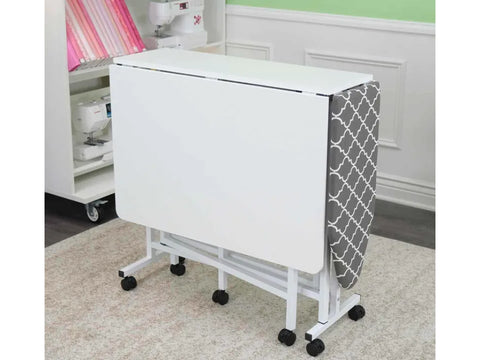 White folding cutting and ironing table with a gray patterned ironing board.