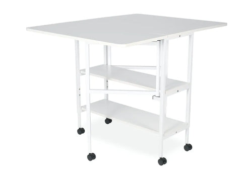 A white folding cutting table with two shelves and wheels.