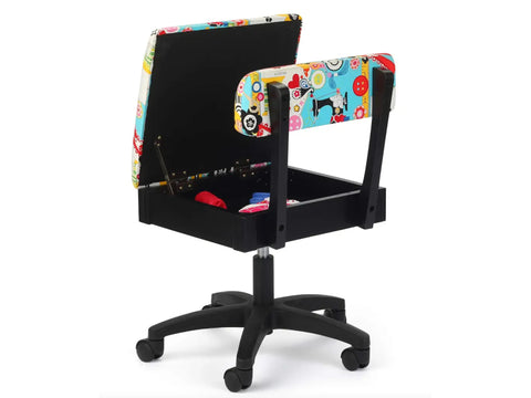 A black hydraulic sewing chair with a colorful sewing-themed fabric, open to reveal storage.