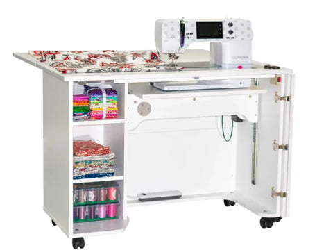 White sewing cabinet with a sewing machine, fabric, and thread.