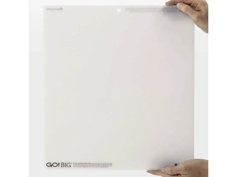A person holds a white AccuQuilt GO! Big 14 by 16 inch cutting mat.