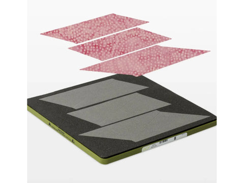 A quilting die with four trapezoidal blades and four pieces of pink polka dot fabric.