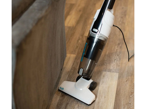 White Simplicity Spiffy bagless stick vacuum on a light wood floor.