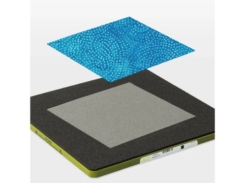 A blue polka dot fabric square floats above a gray and black AccuQuilt GO! die.