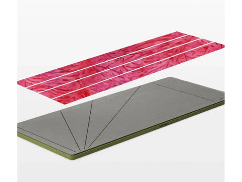 A gray AccuQuilt GO! Strip Cutter die with angled lines and three pink fabric strips.