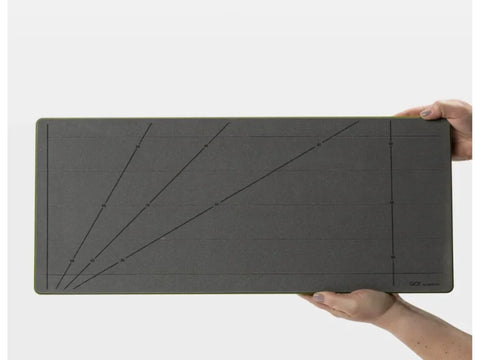 A person holds a gray AccuQuilt GO! Strip Cutter with angled guide lines.