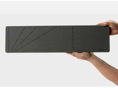 A person holds a dark gray AccuQuilt GO! Strip Cutter with angled guide lines.