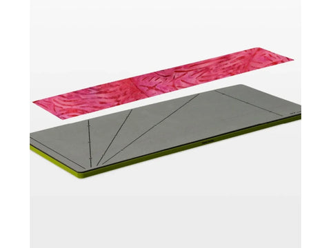 A gray AccuQuilt GO! Strip Cutter with a green edge sits below a pink patterned fabric strip.