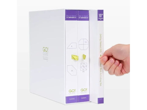 A white AccuQuilt Qube Companion Corners 10" set with a hand pulling out a DVD.