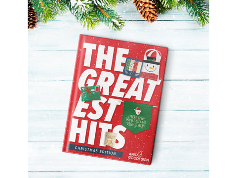 Anita Goodesign Greatest Hits Christmas Edition book on a snowy wooden surface.