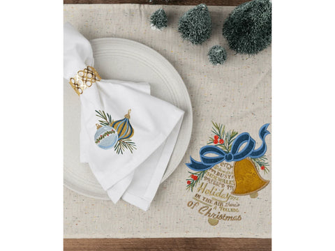 A white napkin with embroidered ornaments and a gold napkin ring on a speckled tablecloth.