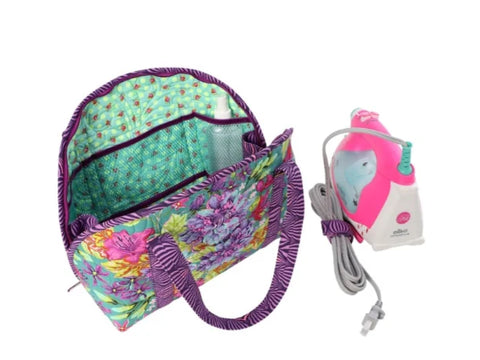 A floral quilted bag with a spray bottle inside and a pink and white iron beside it.