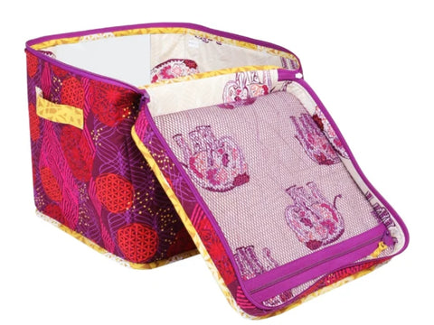 A purple and red patterned fabric storage bin with a partially open zippered lid.