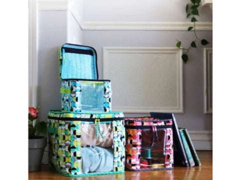 Three patterned storage bins with clear windows are displayed on a wooden floor.