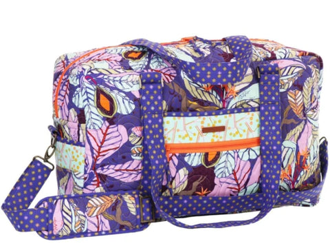 A quilted duffle bag with a vibrant purple, pink, and orange leaf pattern.