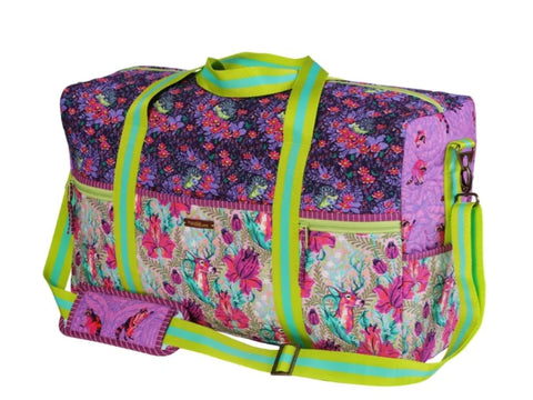 A colorful floral duffle bag with deer and hedgehog patterns and lime green straps.