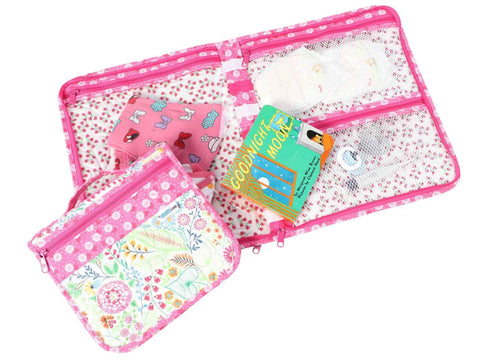 A pink floral patterned organizer with multiple zippered compartments, holding a book and other items.