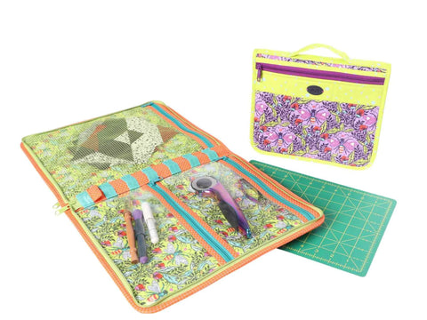 An open and a closed patterned fabric organizer with sewing tools and a cutting mat.