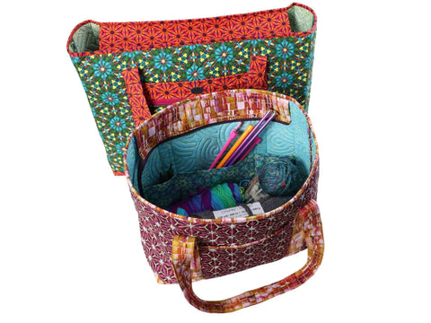 Two large, patterned fabric tote bags, one open and filled with yarn and knitting needles.