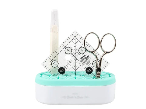 A mint green and white mini organizer holds a seam ripper, ruler, and scissors.