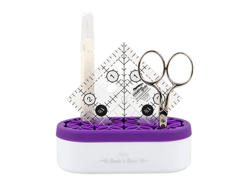 A purple and white Stash N' Store Mini Organizer holds a seam ripper, ruler, and scissors.