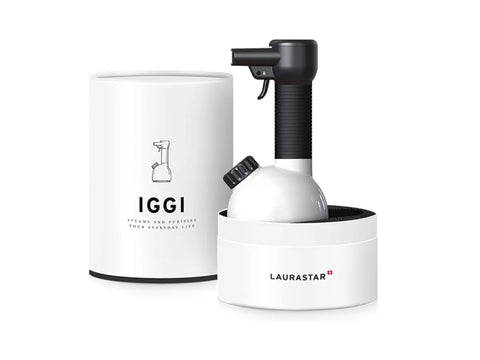 A white and black handheld garment steamer in its white cylindrical packaging.