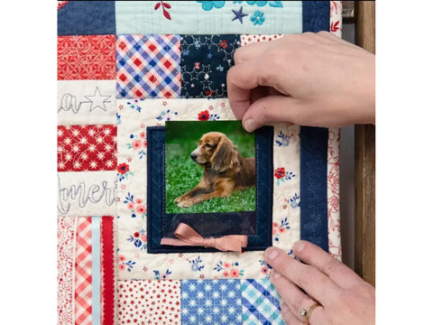 A person's hands place a photo of a dog into a quilt's frame.